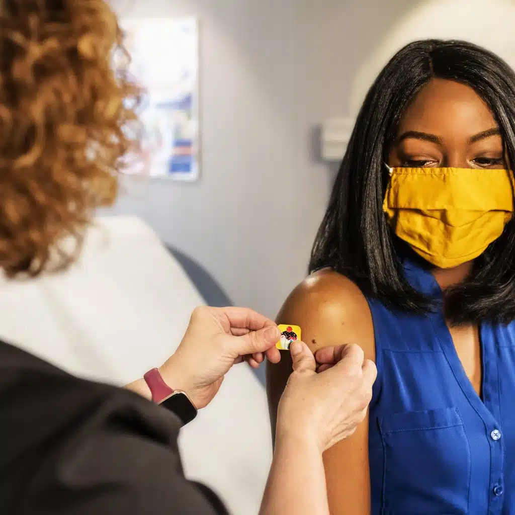 patient and doctor placing a bandaid on arm