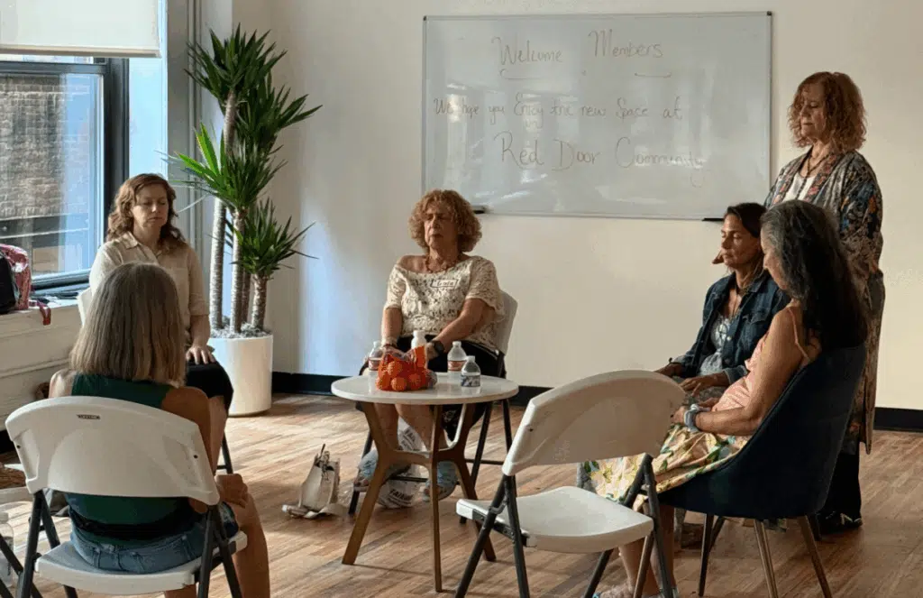 Picture of small group of people sitting in chairs in a circle. Reiki Master Pamela Bloom is practicing her energy work on participants.